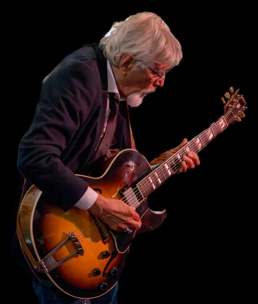 A man playing an electric guitar on stage.