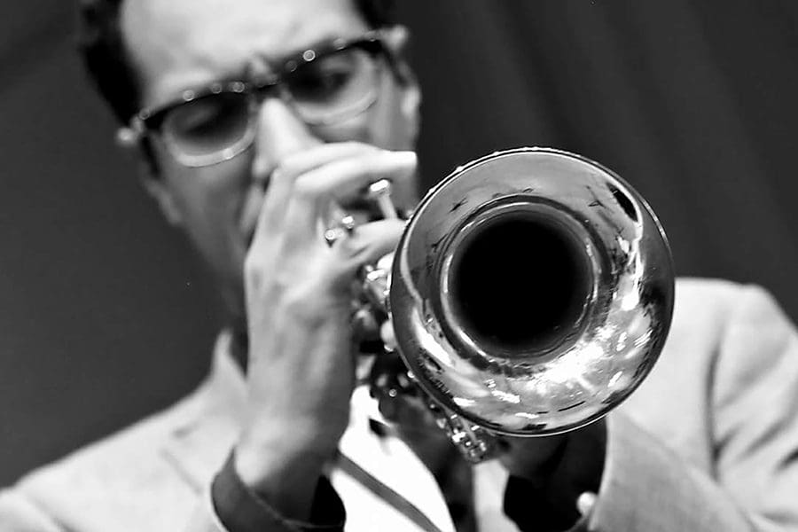 A man playing the trumpet in black and white.