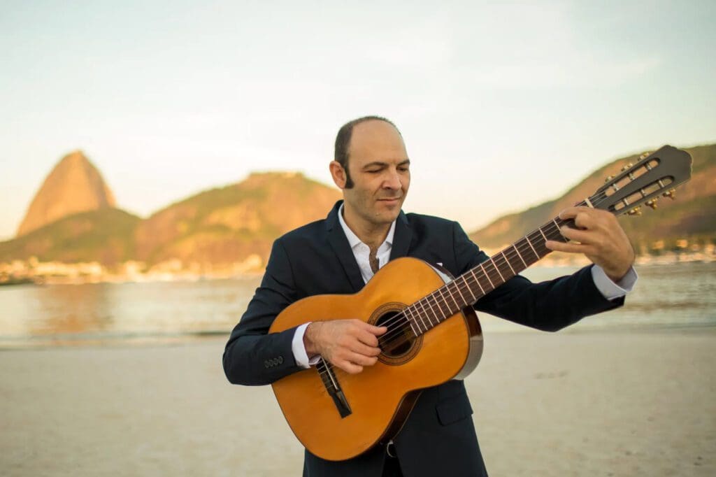 A man in a suit playing an acoustic guitar.